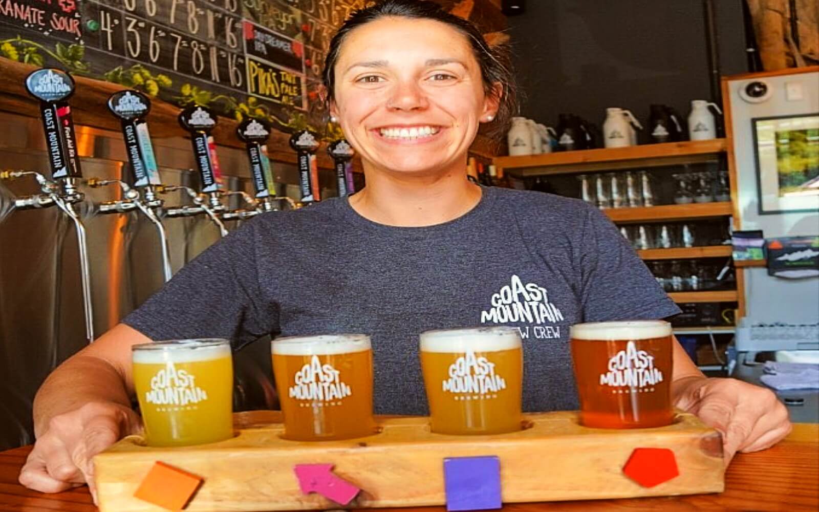 A bartender serves a flight of Coast Mountain beers