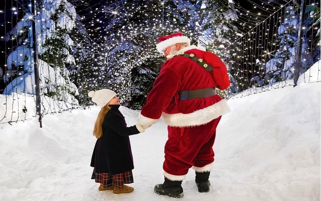 A girl stands with Santa in the Light Walk, Grouse Mountain
