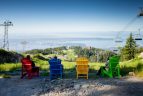 a group of people sitting on muskoka chairs at the top of grouse mountain vancouver bc canada