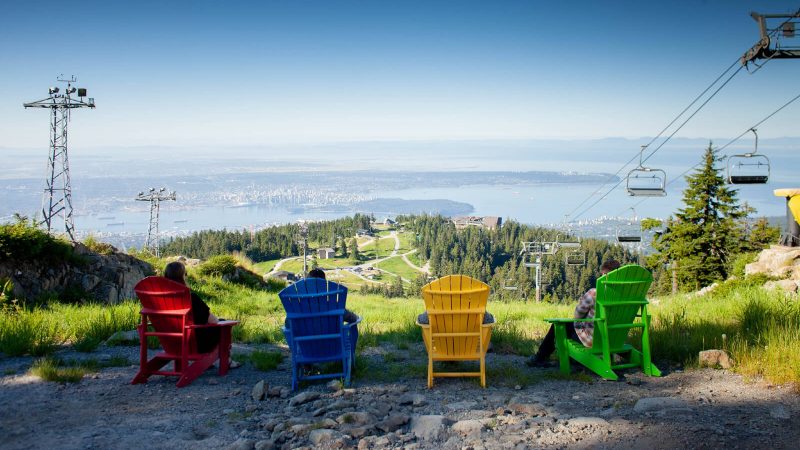 a group of people sitting on muskoka chairs at the top of grouse mountain vancouver bc canada