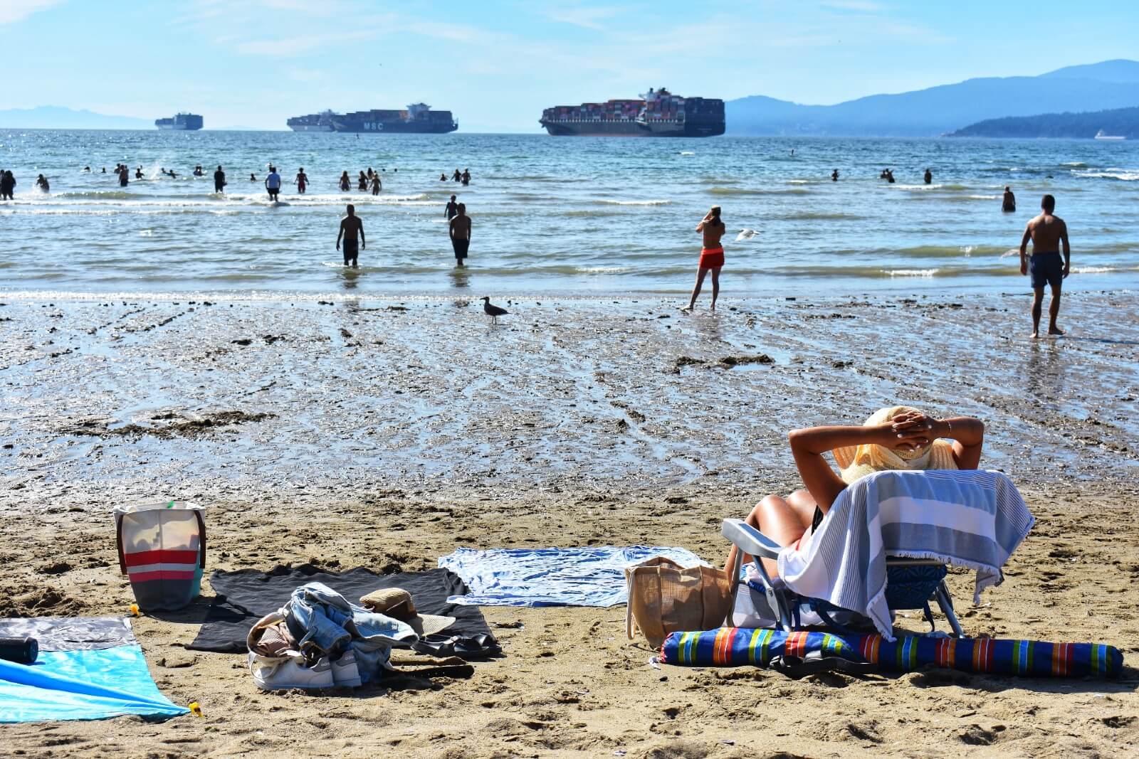 sunbathers relax while swimmers walk into the water at second beach stanley park vancouver bc canada
