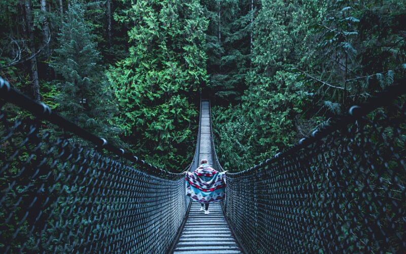a girl crosses the Lynn Canyon Suspension Bridge, one of my favourite Vancouver hidden gems.