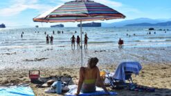 a woman lounging under an umbrella at second beach in vancouver in summer