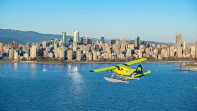 a harbour air sea plane flying in english bay with vancouver skyline