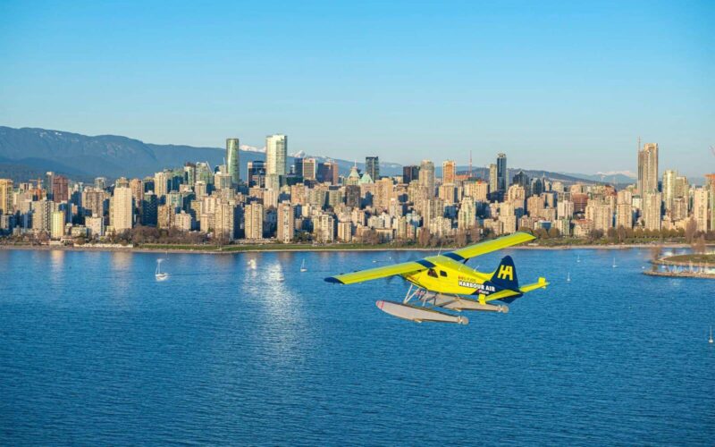 a harbour air sea plane flying in english bay with vancouver skyline