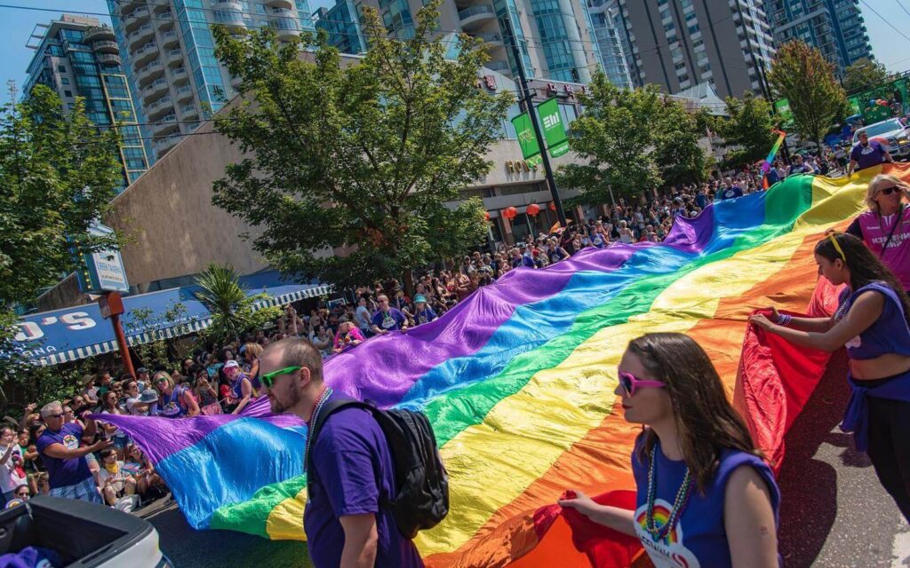 parade goers holding the pride flag at the pride parade in vancouver canada