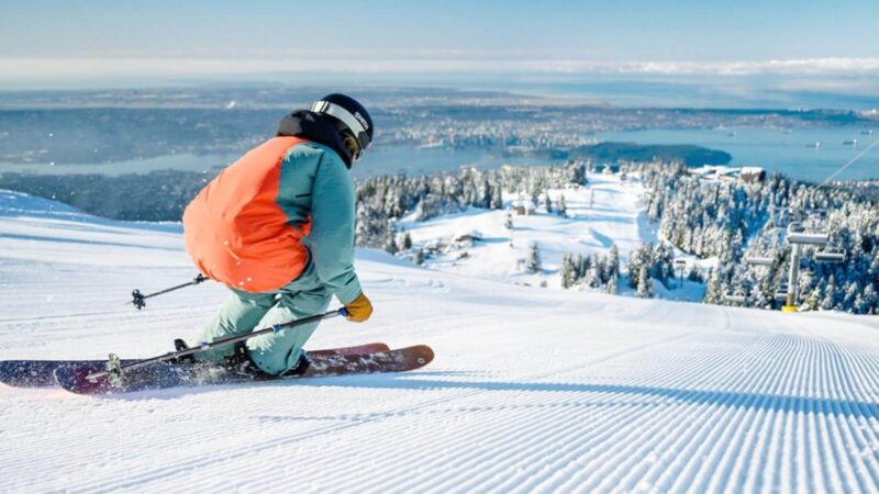 a skier racing down the hill at grouse mountain with vancouver cityscape background