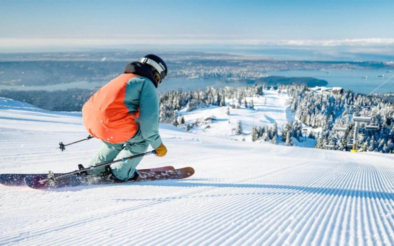 a skier racing down the hill at grouse mountain with vancouver cityscape background