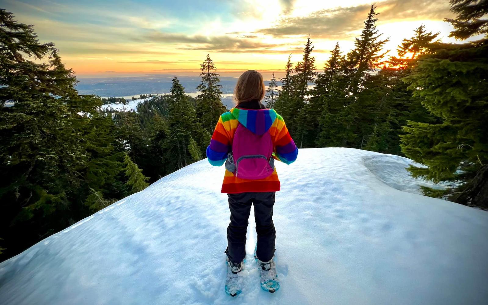 a snowshoer at grouse mountain watching the sunset in vancouver bc canada