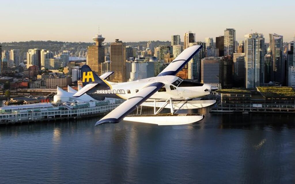 a harbour air seaplane in the skies with vancouver skyline in background