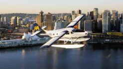 a harbour air seaplane in the skies with vancouver skyline in background