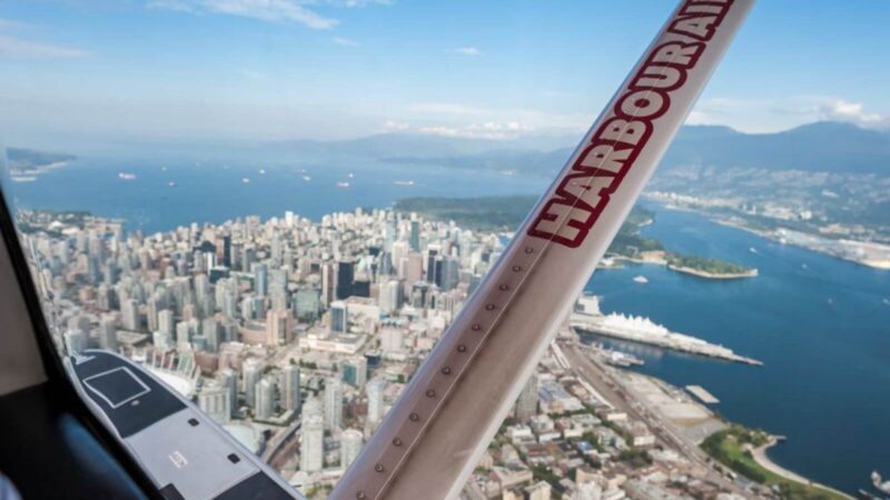 a vancouver seaplane tour flying above the vancouver skyline with coast mountains in background