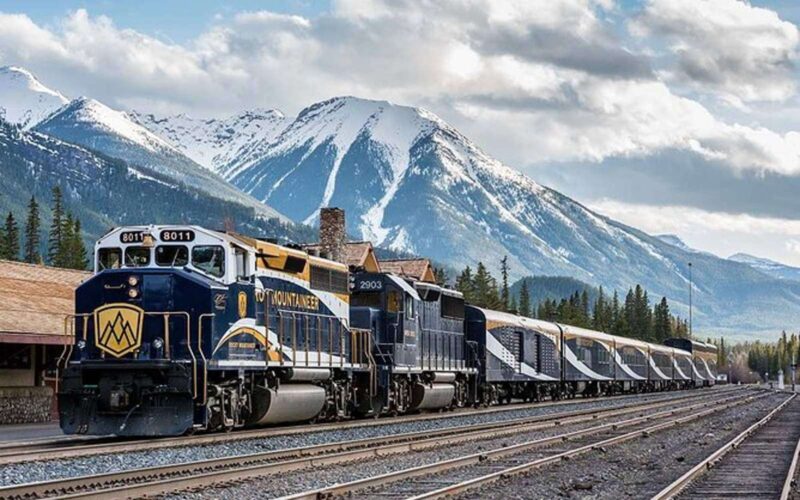 the vancouver to banff train on the tracks in front of the rocky mountains