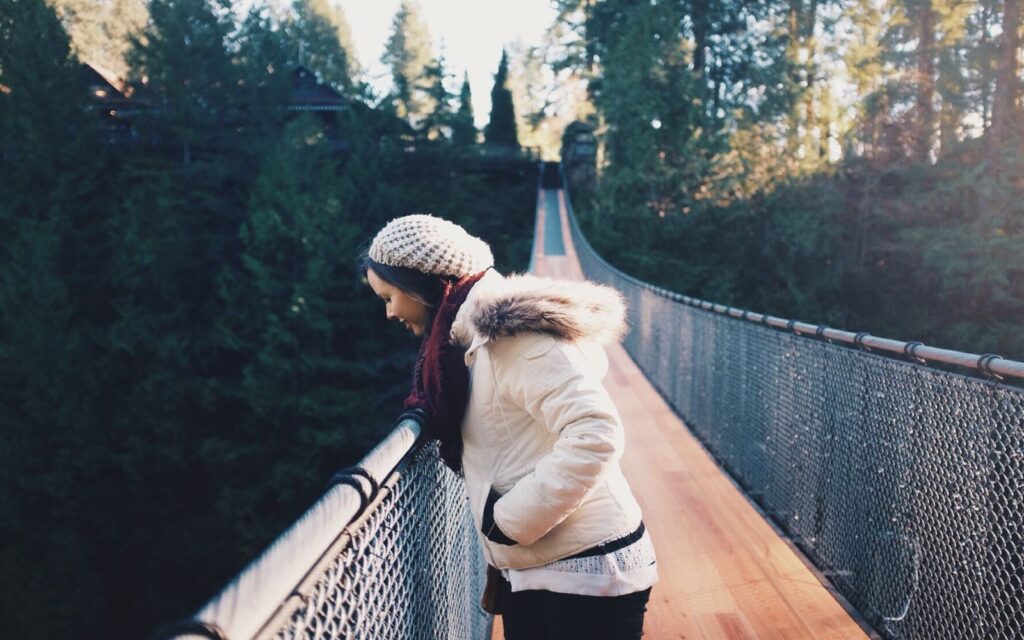 a girl peers over the edge of the capilano suspension bridge in north vancouver, bc.