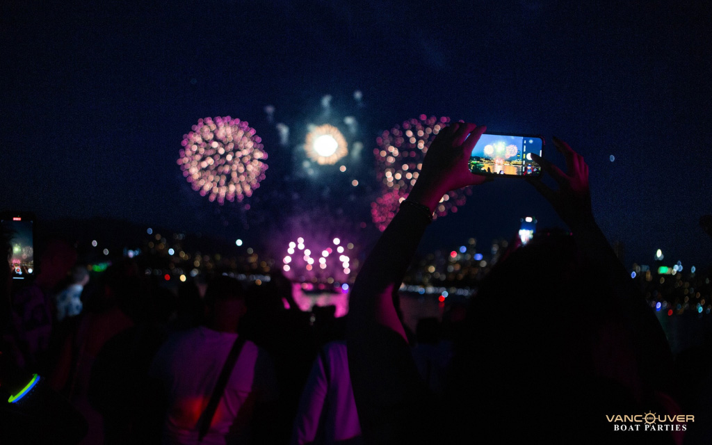 person taking a photo of fireworks during the st. patrick’s day boat party in vancouver bc canada