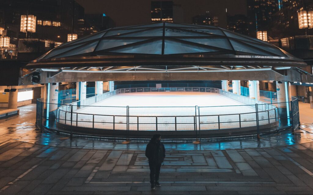 a woman stands next to the robson square ice rink along robson street, vancouver.