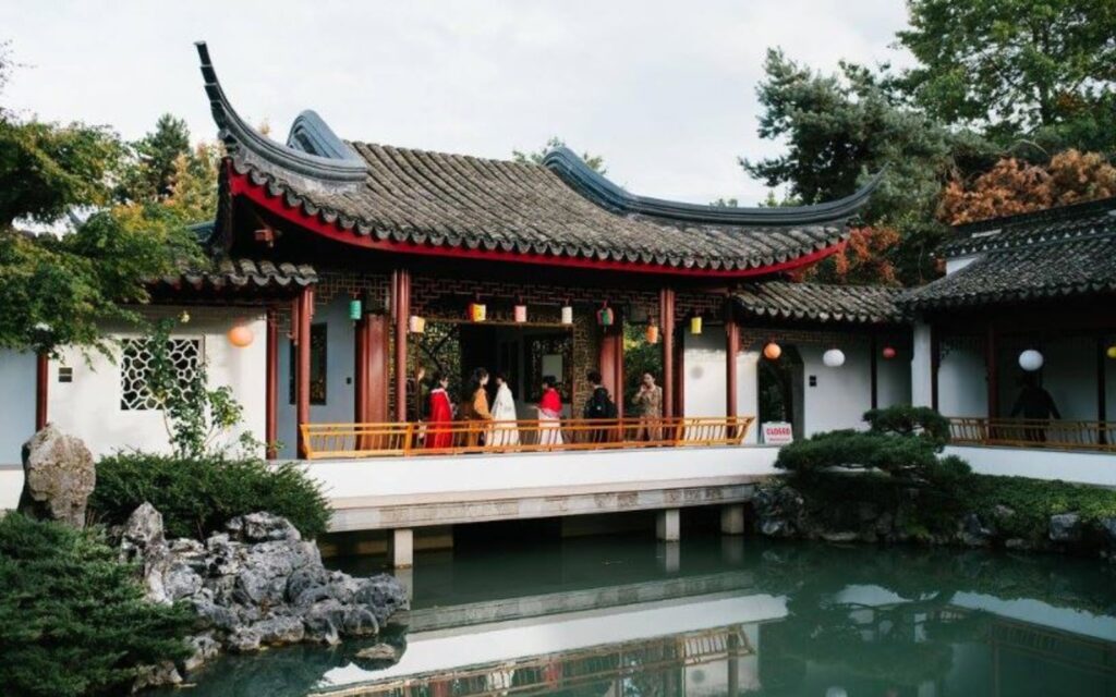 beautiful scenery with hanging lamps in dr. sun yat-sen classical chinese garden with people wearing traditional clothes