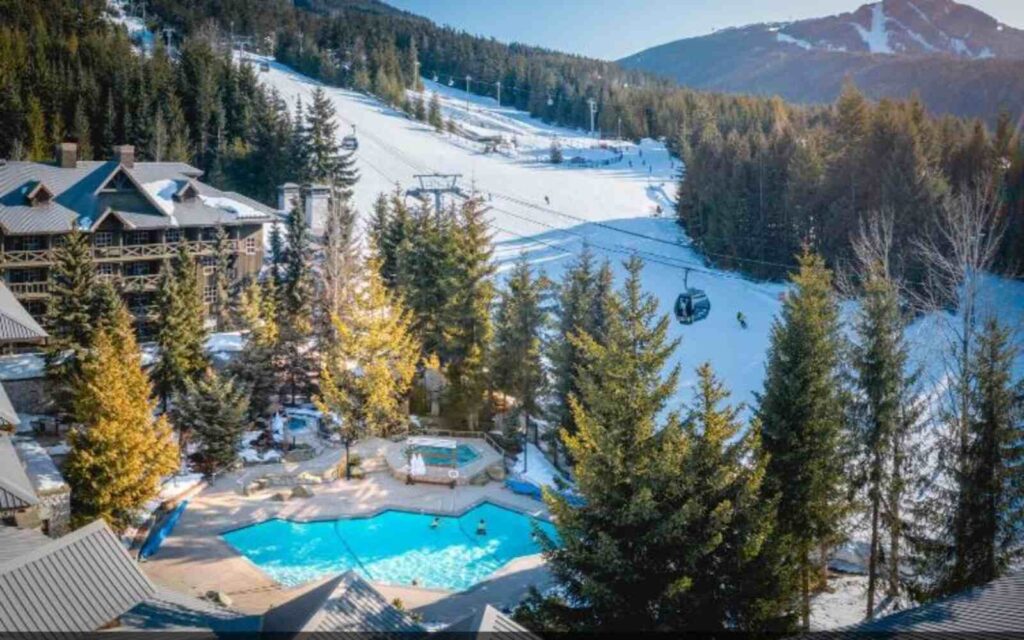 aerial view of blackcomb springs suites showing the pool and the hotel on a snowy weather surrounded by trees