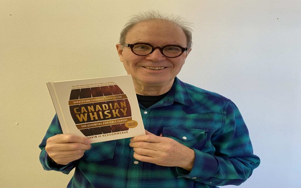 a man holding a book about canadian whisky in bc distilled event
