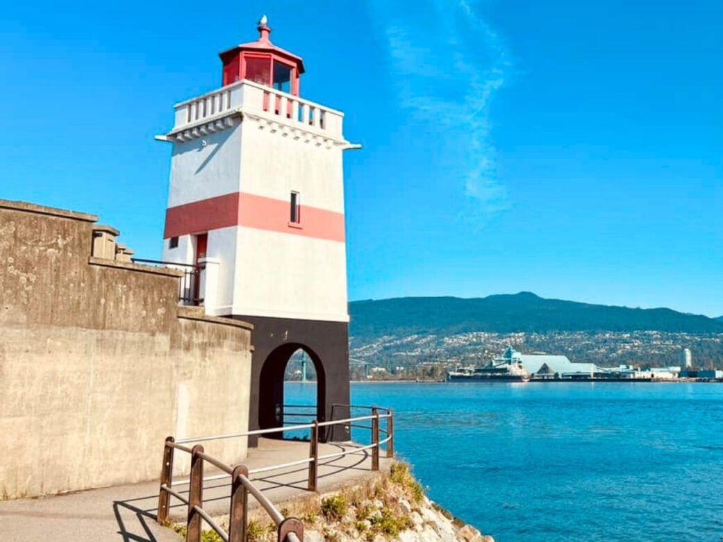 the brockton point lighthouse in its iconic white and red exterior overlooking the sea at brockton point at stanley park