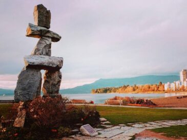 a prominent stone sculpture is positioned near a calm body of water, creating a serene outdoor scene.