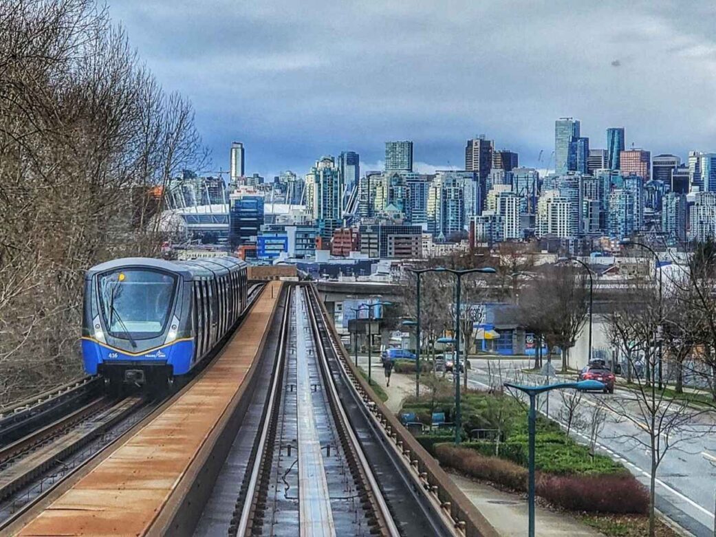 this image shows a vancouver skytrain heading into downtown, with bc place stadium and the city skyline in the background. although the skytrain connects many metro vancouver areas, it does not go directly to tsawwassen ferry terminal. travelers must transfer to a bus or use a ferry connector service.