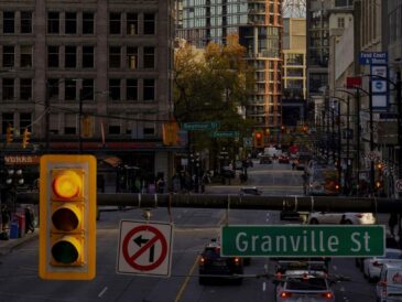 traffic light with different shops and building at the back with a granville street sign