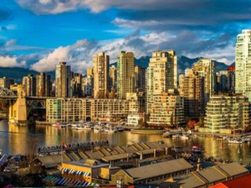 sunlight strikes the high-rises around granville island as boats bob below in false creek—classic vancouver mix of market energy, urban skyline, and waterfront calm