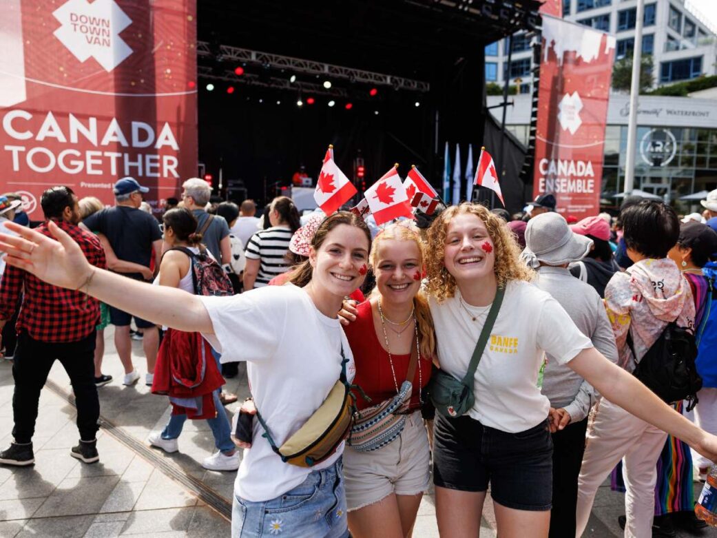 women with canada flags at canada day concert in vancouver at canada place